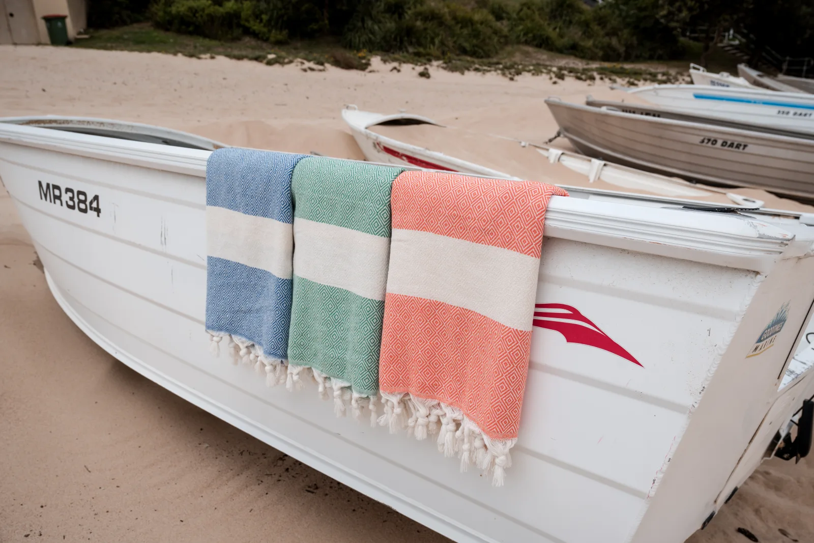Three colourful foutas draped over a white beach boat